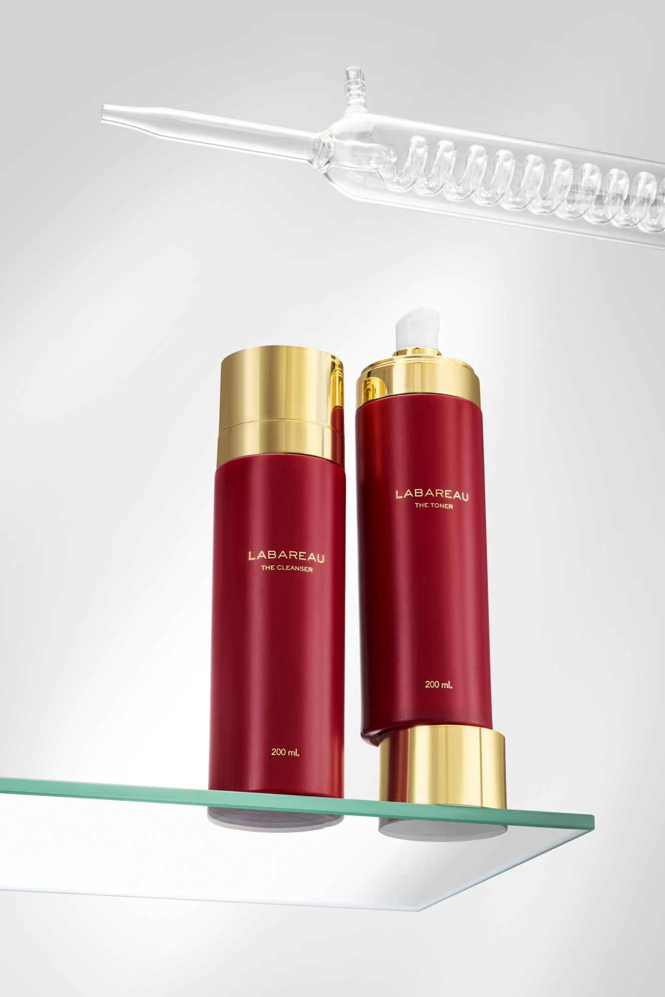 Creatieve beauty productfotografie van Labareau cleanser en toner in rood-gouden verpakking met glazen styling.