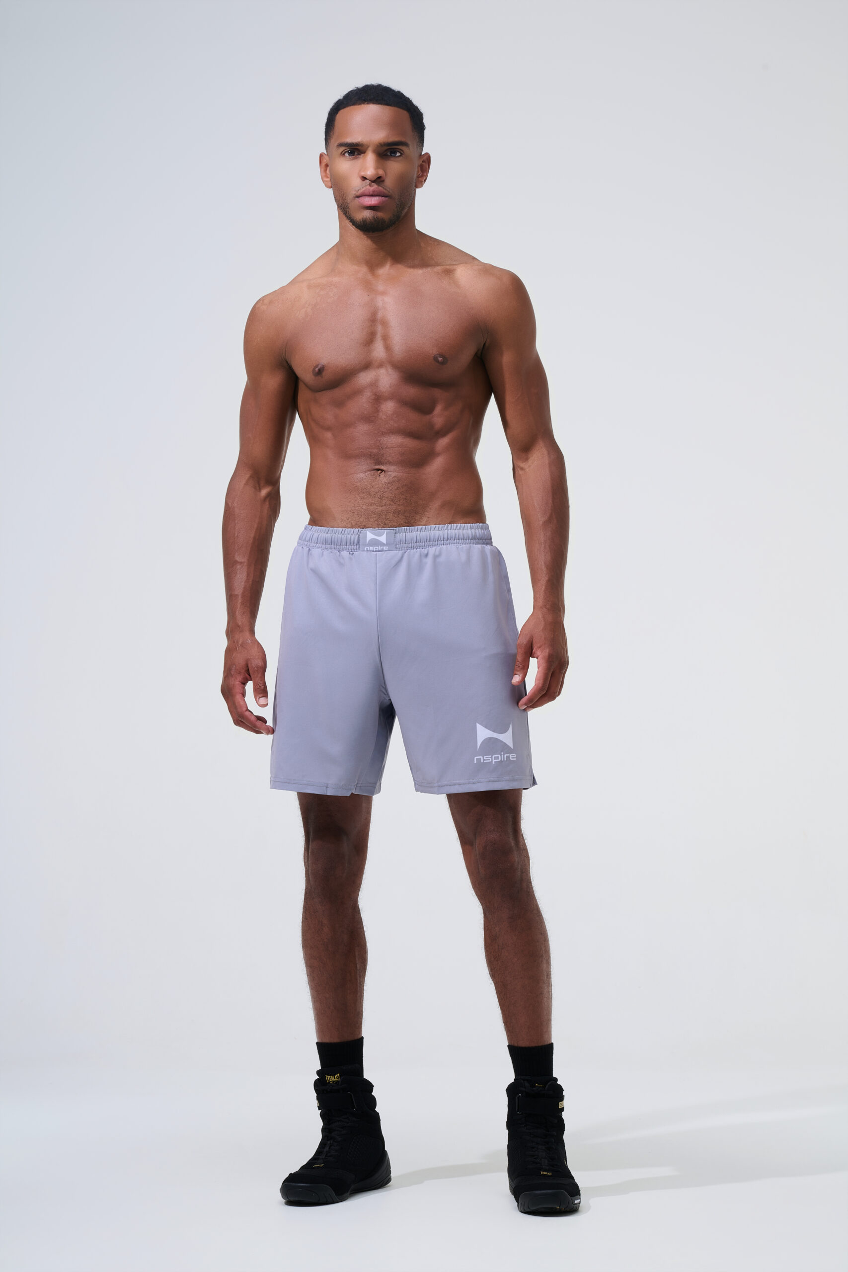 Professionele sportkleding fotografie van mannelijk fitnessmodel in donkerblauwe Nspire sportshort op lichte studioachtergrond.