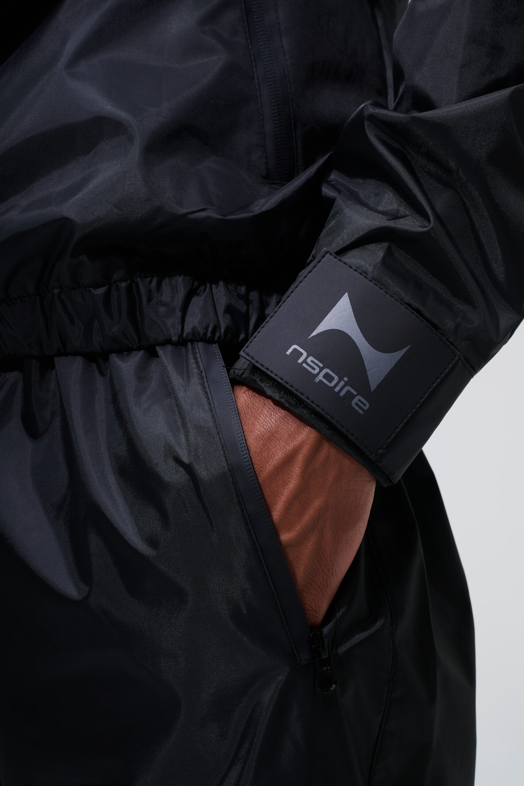 Detailfotografie van zwarte Nspire sportkleding met zichtbaar logo, technische stof en ritsdetail.
