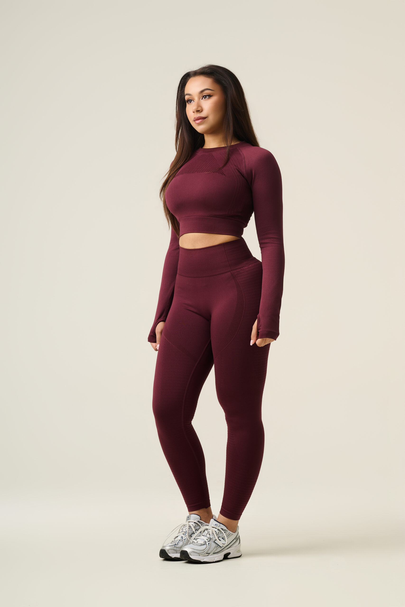 Fashion fotografie van vrouwelijk model in bordeauxrode seamless sportset met lange mouwen en high-waist legging.