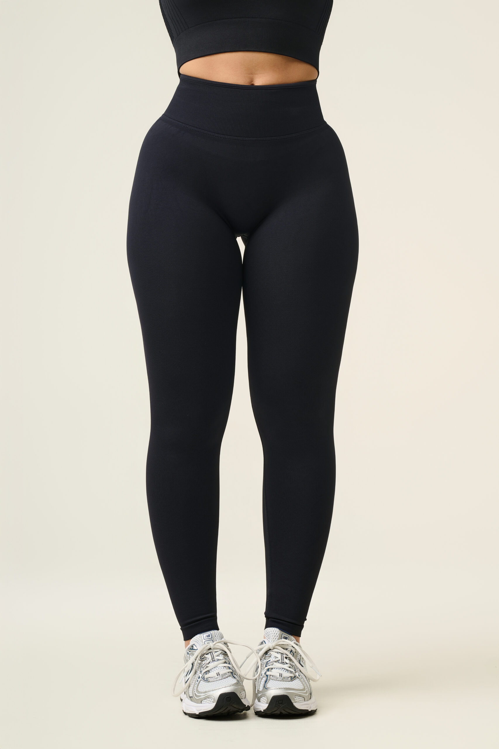 Professionele sportkleding fotografie van vrouwelijk model in zwarte high-waist sportlegging en crop top in studio.
