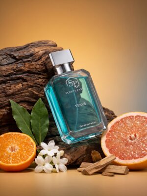 Fles Venus Extrait de Parfum van Scents Paris met turquoise parfum, gefotografeerd tussen hout, groene bladeren, witte bloemen, sinaasappel en grapefruit.