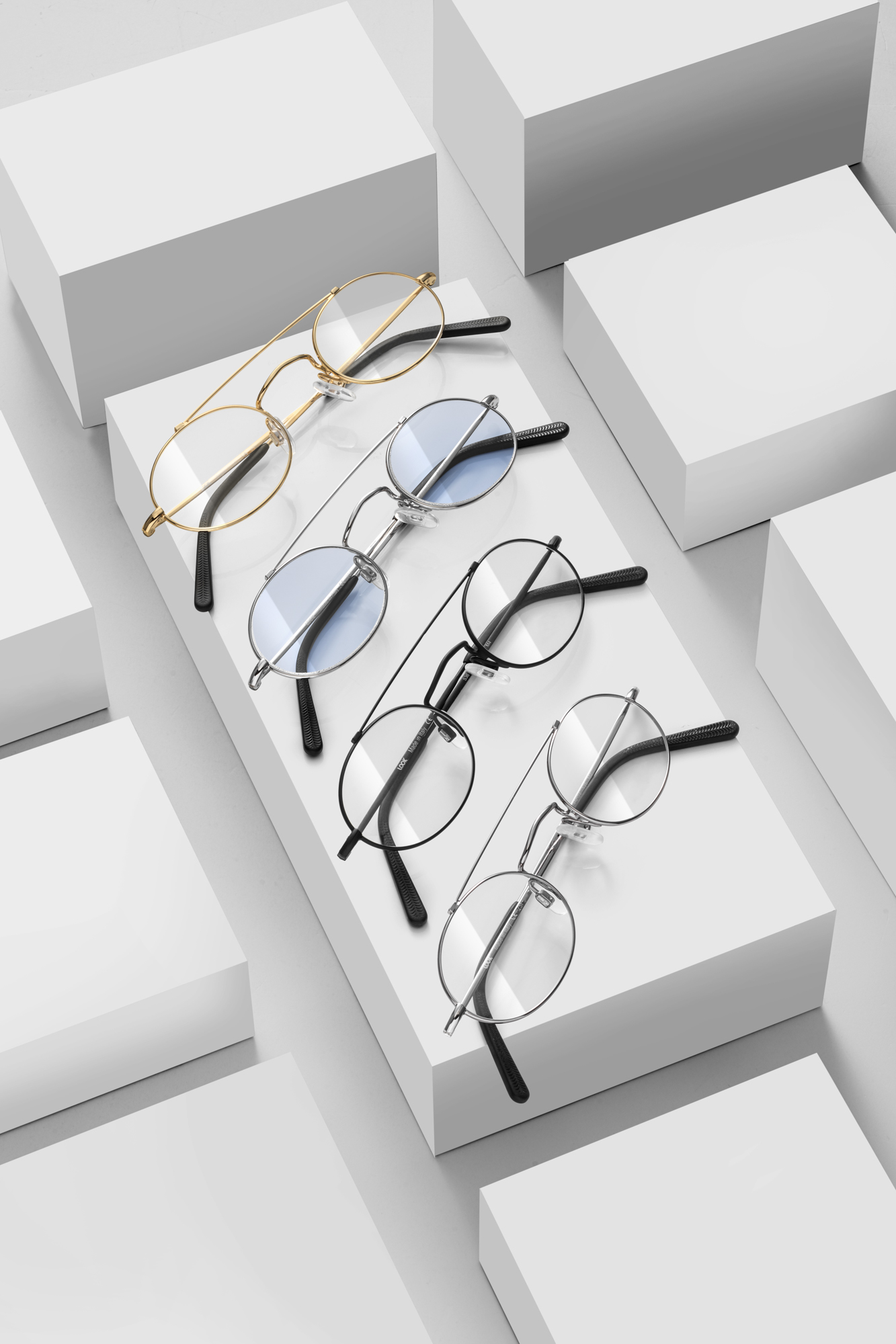 Commerciële productfotografie van meerdere metalen brillen en monturen op witte blokken voor een professionele eyewear collectie